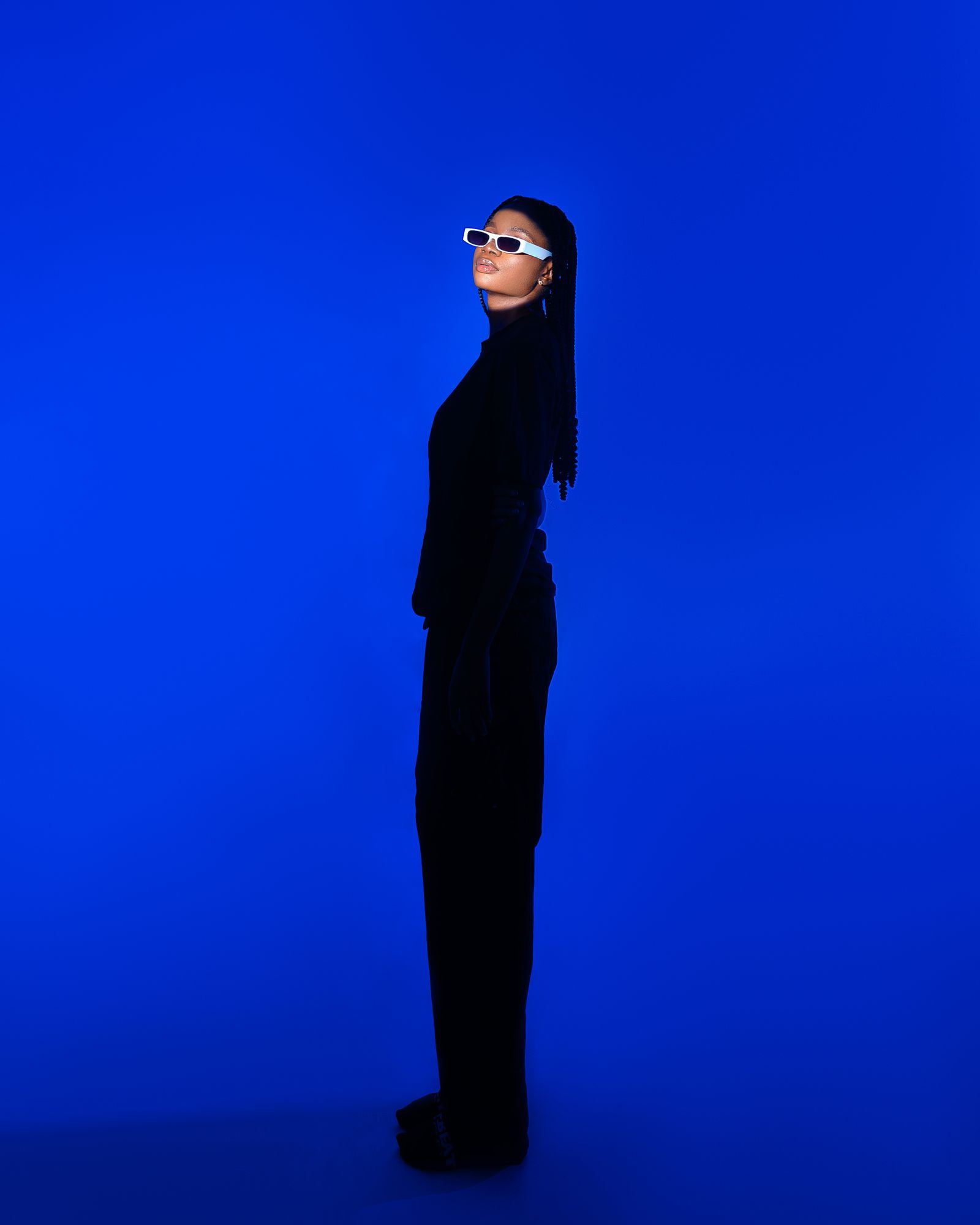 Model wearing Kaleido Arctic Rectangle frames against an electric blue backdrop