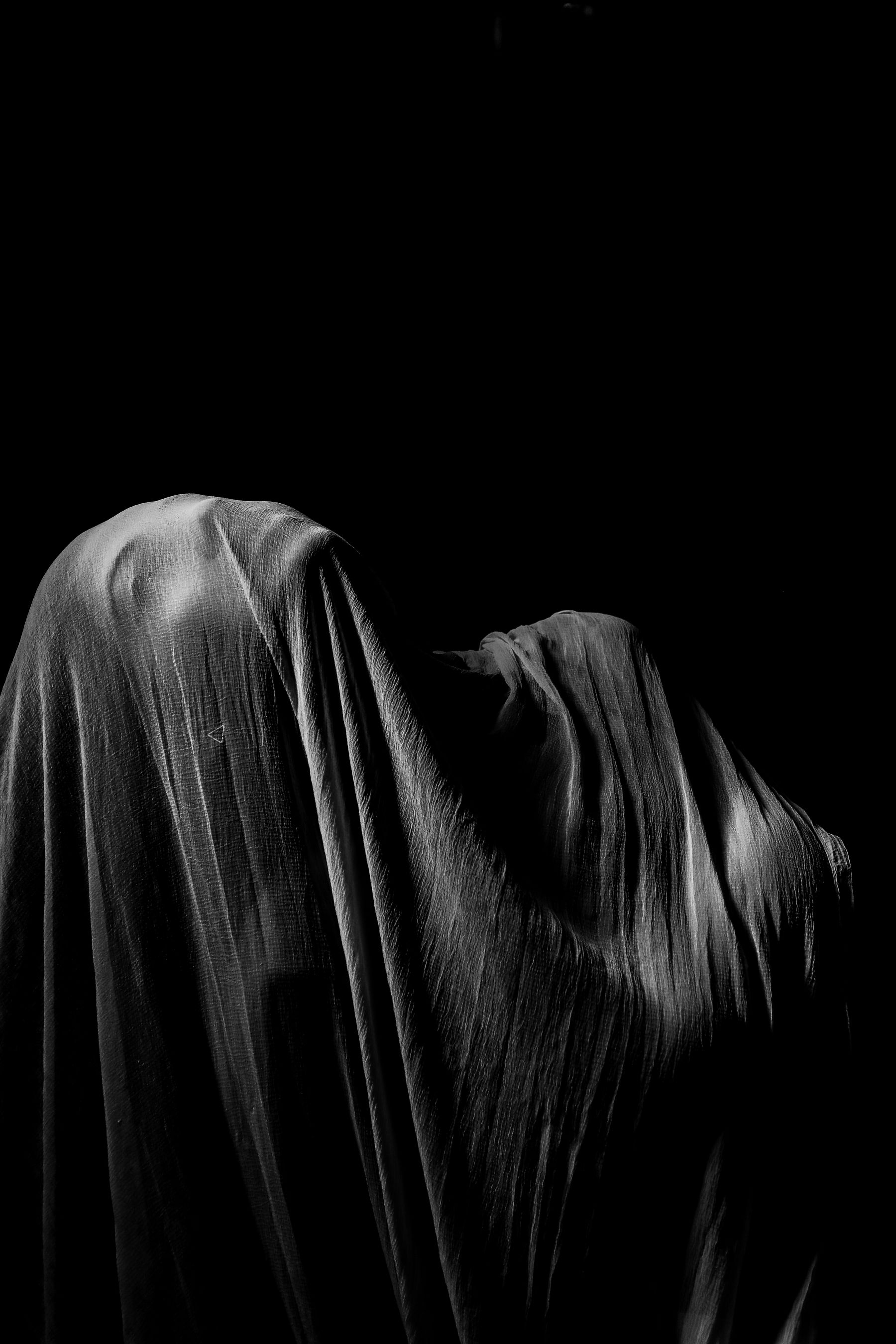 Heavyweight cloth draped over a figure under raking light